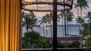 Una habitación con vista al océano, una lámpara colgante y muebles de mimbre.
