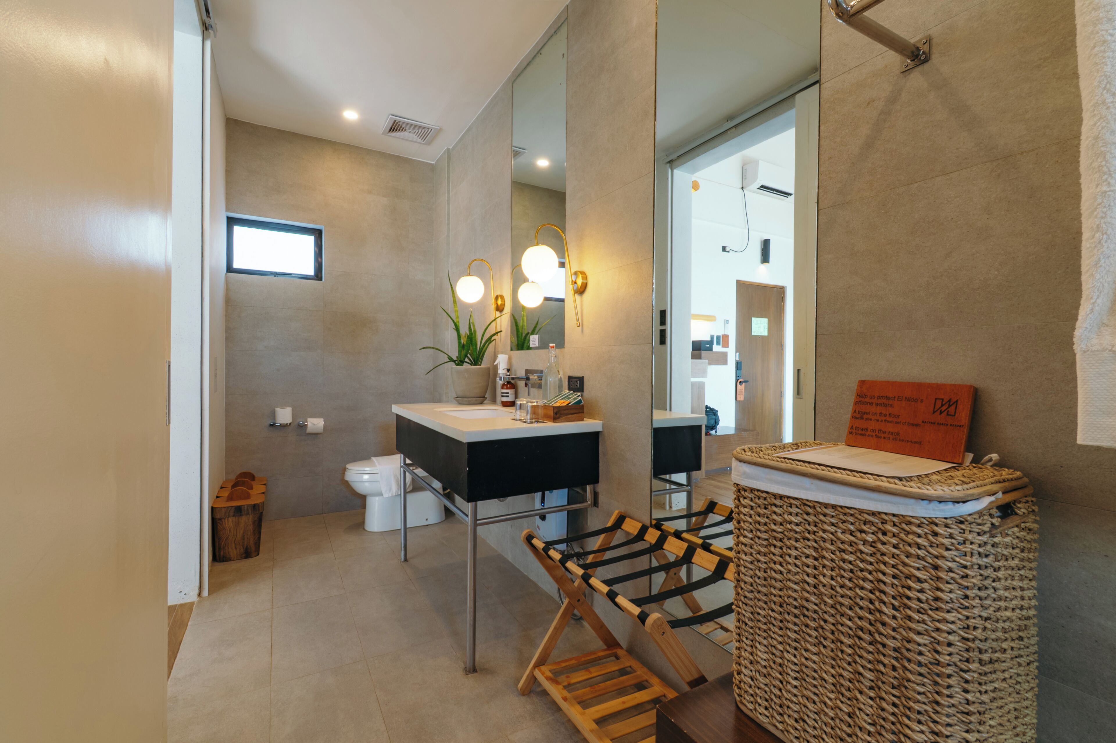 Un baño moderno con un espejo grande, un lavabo y una cesta de mimbre.