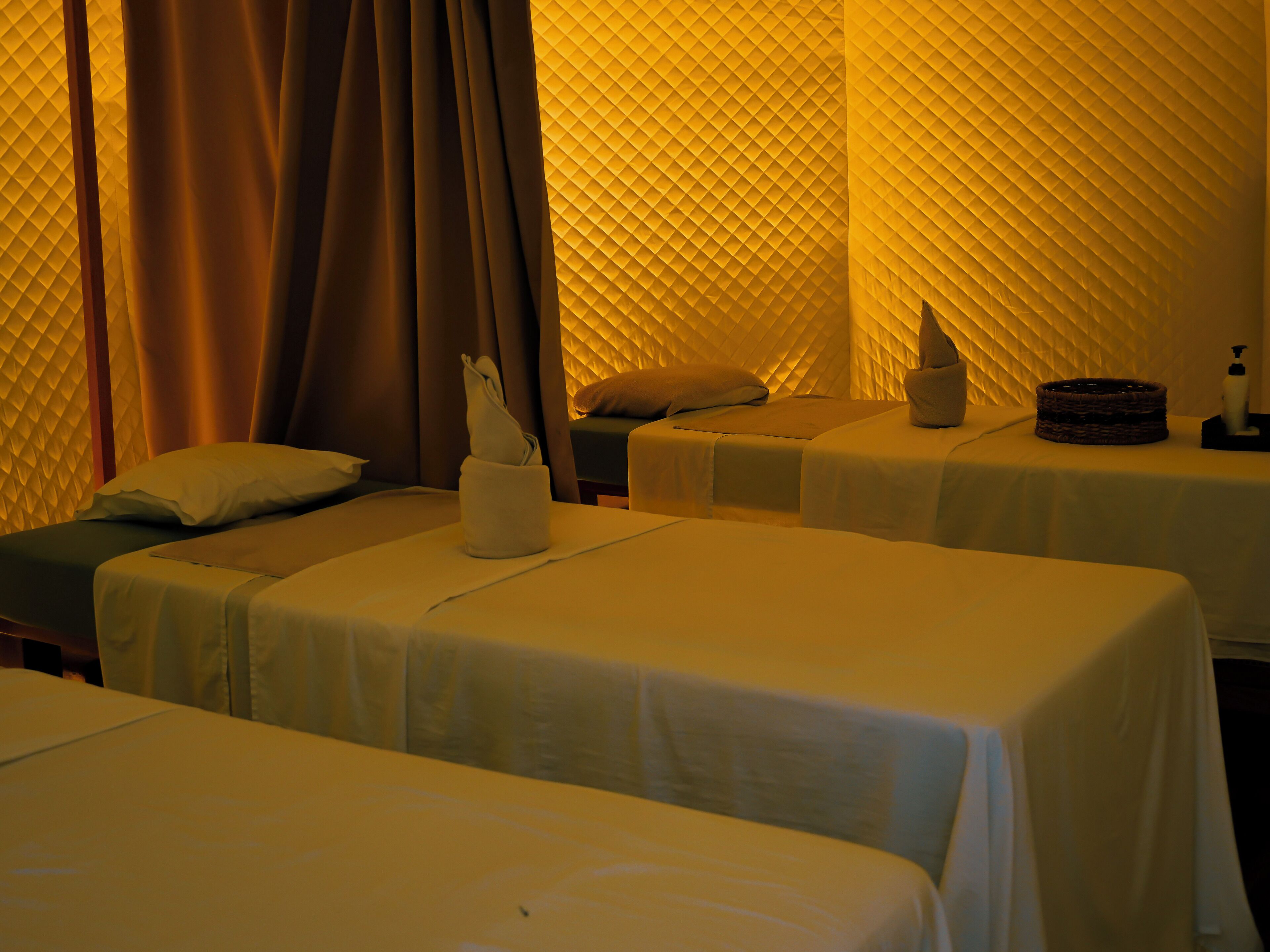 Une chambre avec trois lits, chacun étant équipé d’un oreiller et d’une petite table de chevet.