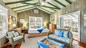 A cozy room with a bed, two wicker sofas, a coffee table, and a ceiling fan.