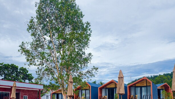 A swimming pool with lounge chairs and umbrellas, surrounded by wooden cabins with large windows. -  Beach  just a few steps away, offering easy access to the island’s attractions. (Preah Sihanouk)