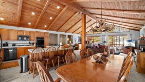 Une cuisine spacieuse avec des meubles en bois, un coin repas doté d’une grande table et un lustre.