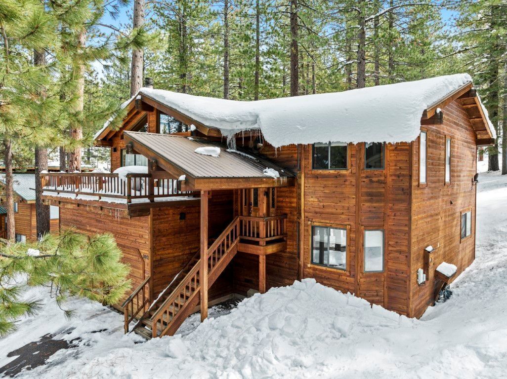 Une cabane en bois dotée d’un porche couvert et d’un escalier menant à l’entrée.
