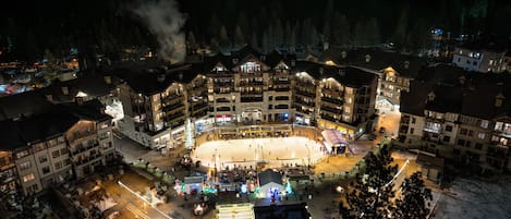 Un hotel grande de varios pisos con un patio central, rodeado de nieve en el suelo y árboles.