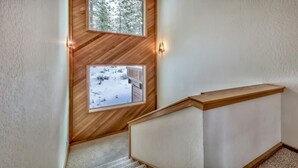 Eine Holztreppe mit Blick auf eine verschneite Landschaft durch ein Fenster.