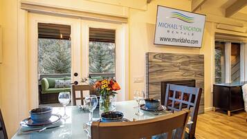 A dining area with a glass table set for four, a fireplace, and a sign for Michael's Vacation Rentals.
