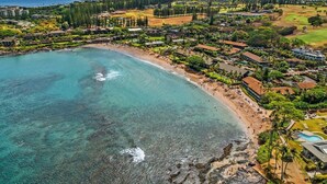 An aerial view of a coastal resort with a beach, clear waters, and a mix of residential and hotel buildings. - Studio Relaxing Garden View Retreat Near Napili Bay & Ocean-Napili Shores D230 (Lahaina)