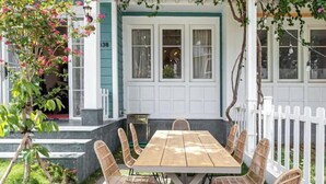 A covered patio with a wooden table and wicker chairs, a white picket fence, and a house number 38. - 3 bedroom Villa Venus House Phan Thiet (Phan Thiet)