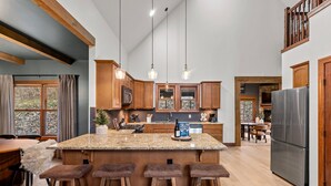 A spacious kitchen with a large island, wooden cabinets, and a stainless steel refrigerator.