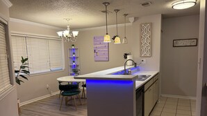Una cucina moderna con isola centrale, luci a sospensione e lavastoviglie integrata.