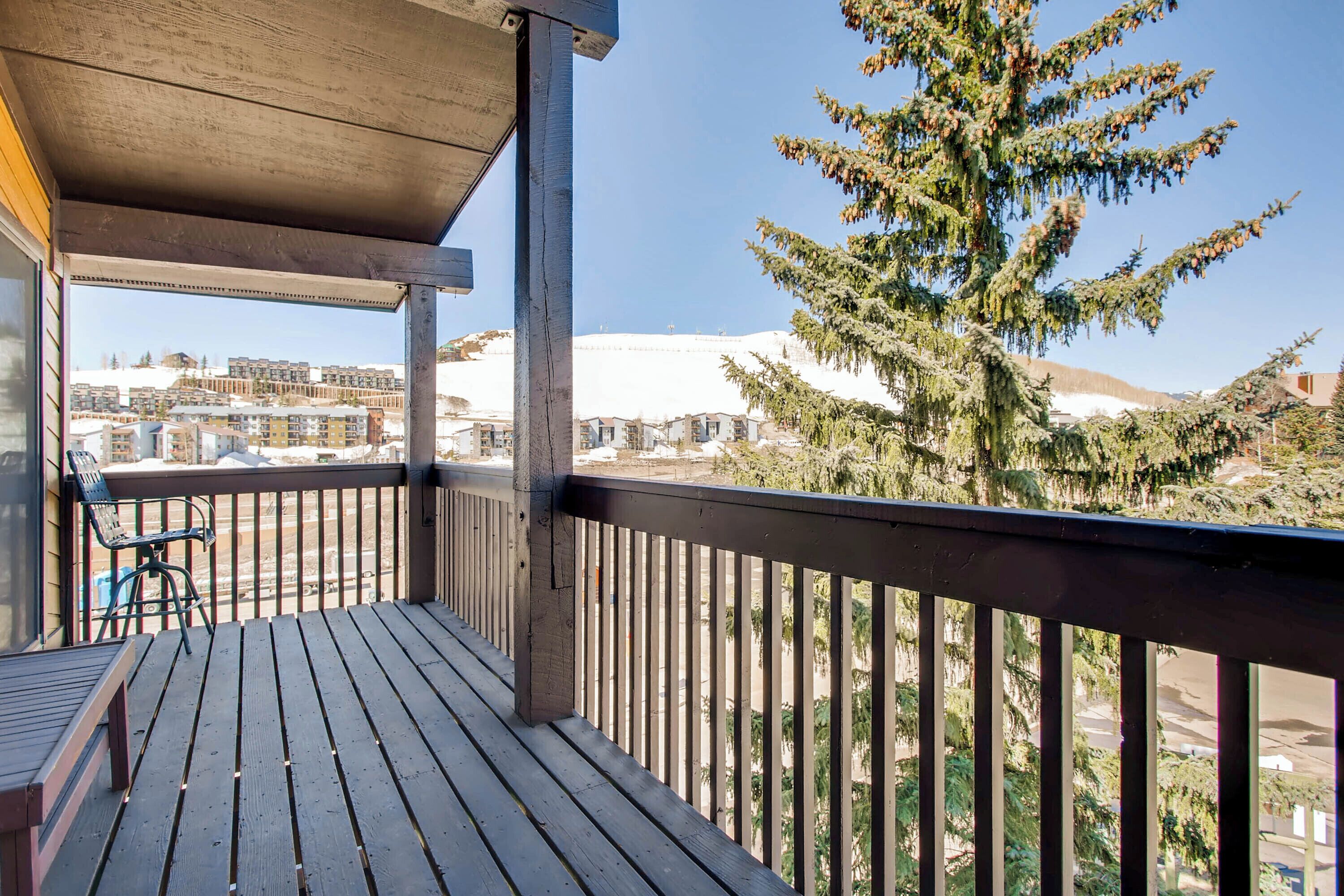 Un ponte di legno con vista su edifici e un grande abete sempreverde.