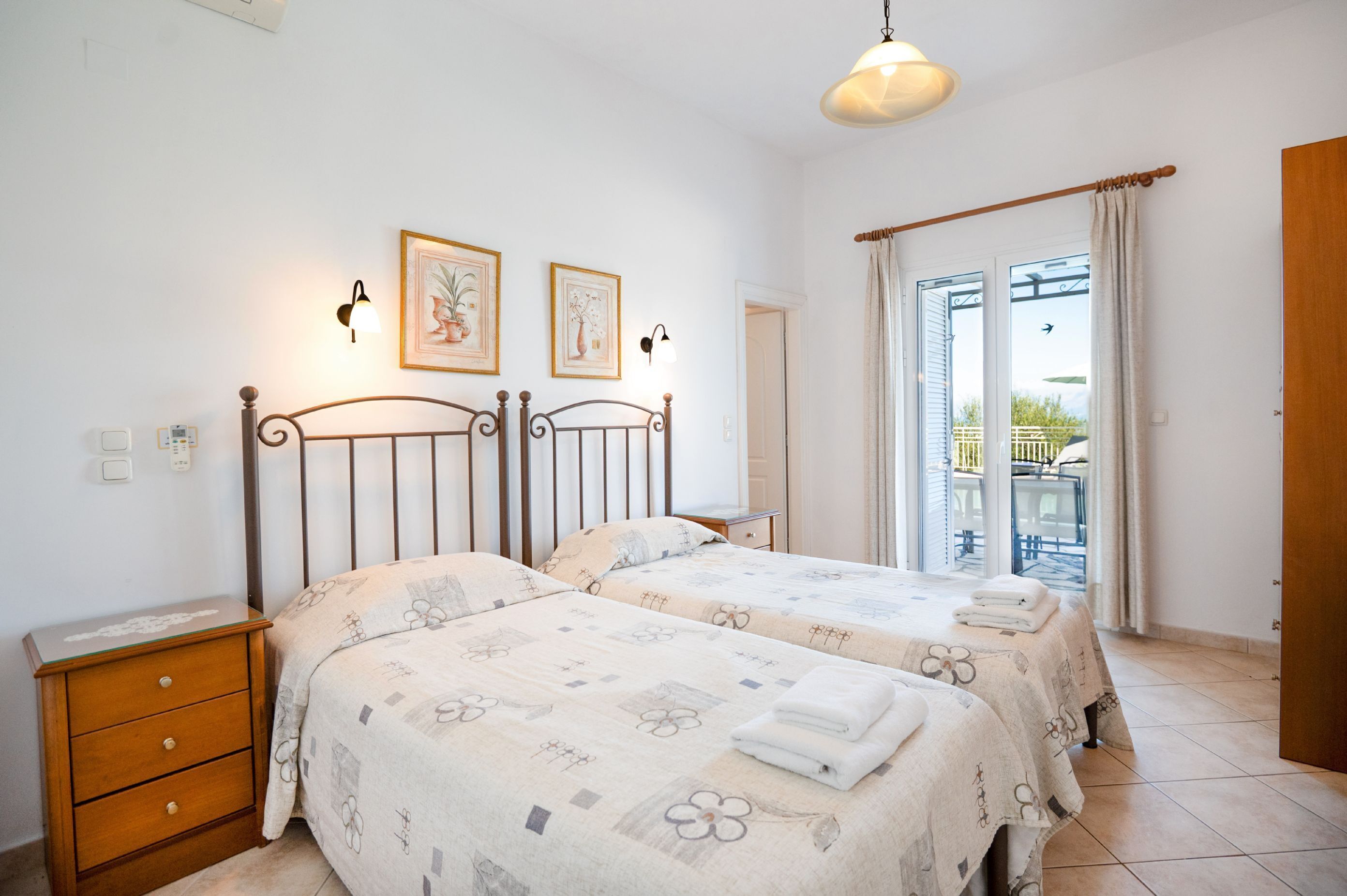 A bedroom with two beds, a nightstand, and a window with curtains.