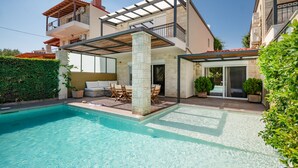 Une maison moderne à deux étages, dotée d’une piscine, d’un espace salon extérieur et d’un patio couvert.