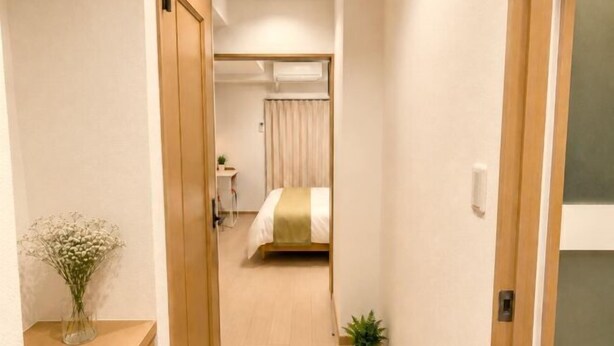 A hotel room with a bed, bedside table, and a small plant. - YMK Oshiage 7A (Tokyo)