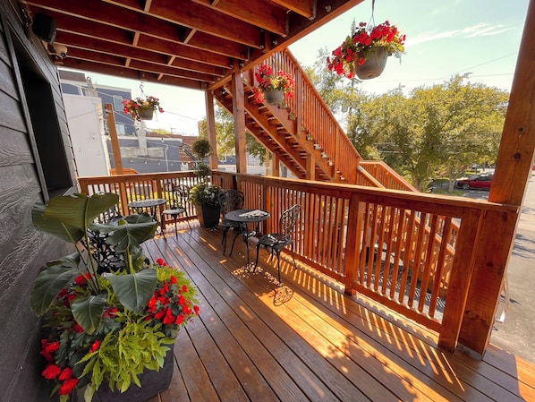 A wooden deck with a staircase, potted plants, and outdoor furniture.