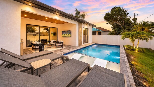 Ein moderner Poolbereich im Freien mit Terrasse, Sitzgelegenheiten und Blick auf den Himmel.