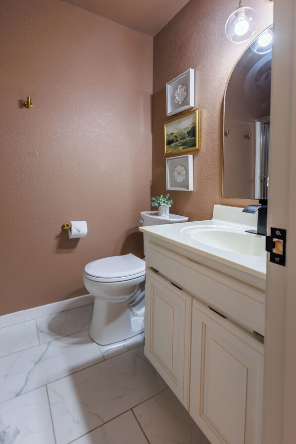 A bathroom with a toilet, sink, and mirror. - Coler Bike-N-Go Fully Fenced 3bd/3ba Sleeps 8 (Bentonville)