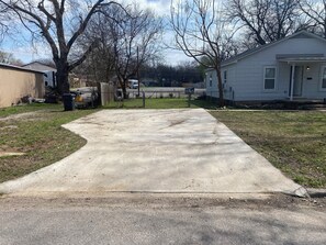 Una strada di cemento che conduce a una casa con garage e cortile recintato.