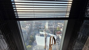 Ett modernt badrum med ett stort badkar, en utsikt över stadsbilden genom fönstret och en vy över området nedanför.