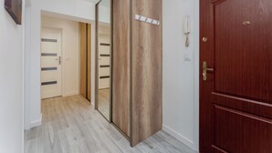 A hallway with a wooden wardrobe, a wooden door, and a mirror. - Bronowice Spacious Apartment (Kraków)