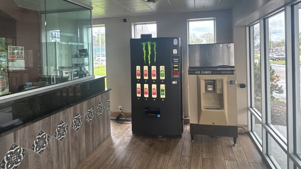 Un interior moderno con un mostrador de recepción, un dispensador de bebidas y un dispensador de hielo.