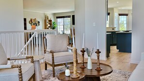 A spacious living room with a high ceiling, a staircase, and a view to the kitchen. - Stunning Bayside View Retreat; Resort, Pools & Gym (Berlin)