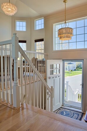 Un intérieur spacieux avec un escalier, de grandes fenêtres et un lustre.