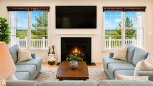 A living room with a fireplace, two sofas, a coffee table, and a TV. - Stunning Bayside View Retreat; Resort, Pools & Gym (Berlin)