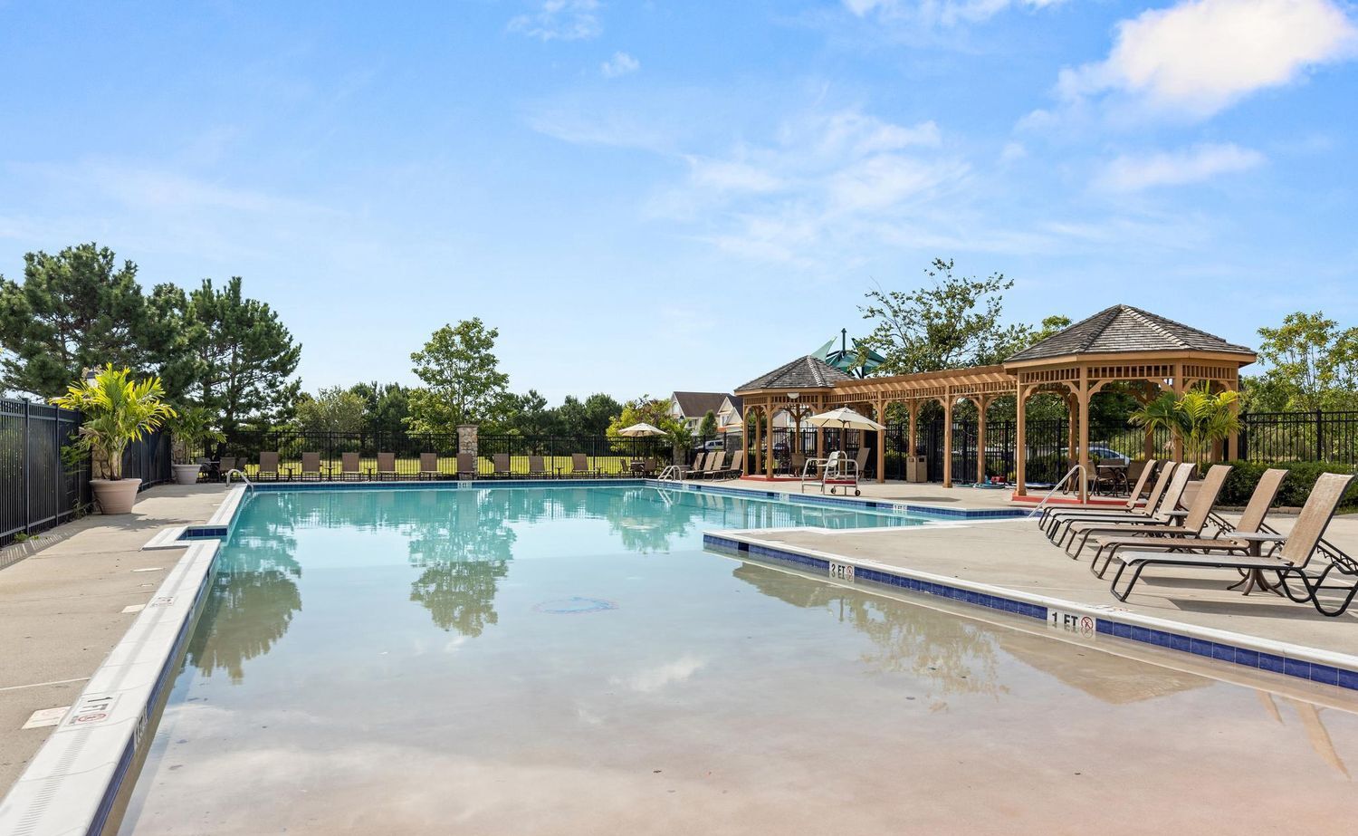 A swimming pool with lounge chairs and a gazebo.