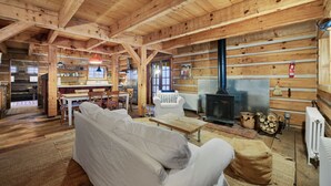 L’intérieur d’une cabane en rondins comprend un canapé, une table à manger, un coin cuisine et un poêle à bois.