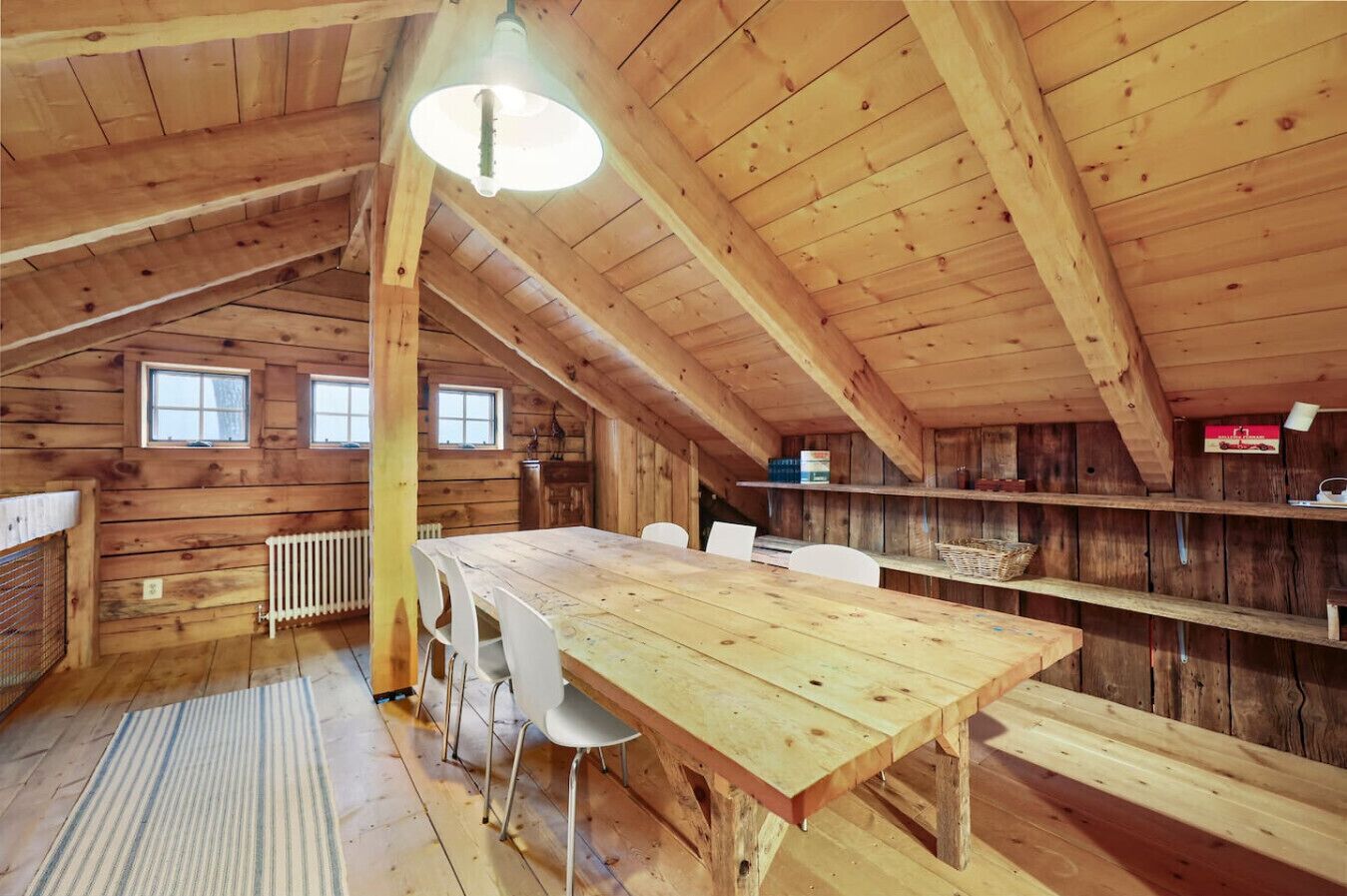 A wooden interior with a dining table, chairs, and a radiator.