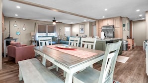 Un espacio habitable amplio con mesa de comedor, asientos y una cocina equipada con refrigerador y alacenas.