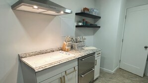 A modern kitchen with white cabinets, a granite countertop, stainless steel appliances, and a built-in oven.