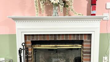 A fireplace with a white mantel, a vase with sunflowers, and a fire extinguisher on the wall.