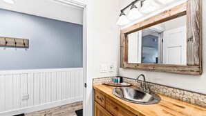 Une salle de bain avec un meuble-lavabo en bois, un grand miroir et un évier.