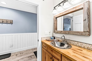 A bathroom with a wooden vanity, a large mirror, and a sink.