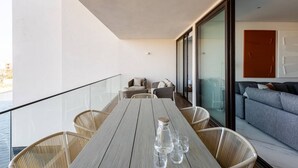 Ein Balkon mit Holztisch, Korbstühlen und einer Sitzecke.