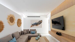 Ein modernes Wohnzimmer mit einer Eckcouch, einem Couchtisch, einem Flachbildfernseher an einer Holzwand und einem großen abstrakten Gemälde.