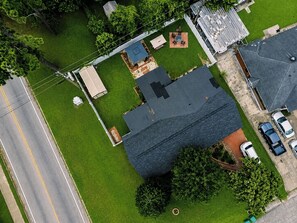 Un barrio residencial con una casa que tiene un garaje amplio, un patio cercado y una calle con línea amarilla doble.