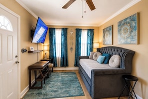 A living room with a sofa, a television, and a ceiling fan. - Screened Porch • Gazebo • BBQ • Sleeps 10 (Garden City)