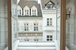 Vista da janela com vista para um edifício com várias janelas e uma escadaria que leva a um andar superior.