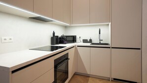 Moderni keittiö, jossa on valkoiset kaapit, musta työtaso, sisäänrakennettu uuni, mikroaaltouuni ja pesuallas.