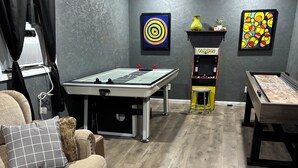 A room with a pool table, a foosball table, a sofa, and two wall-mounted gaming machines. - One-level Family Retreat I  Game Room I Bourbon Trail I King bed (Lebanon)