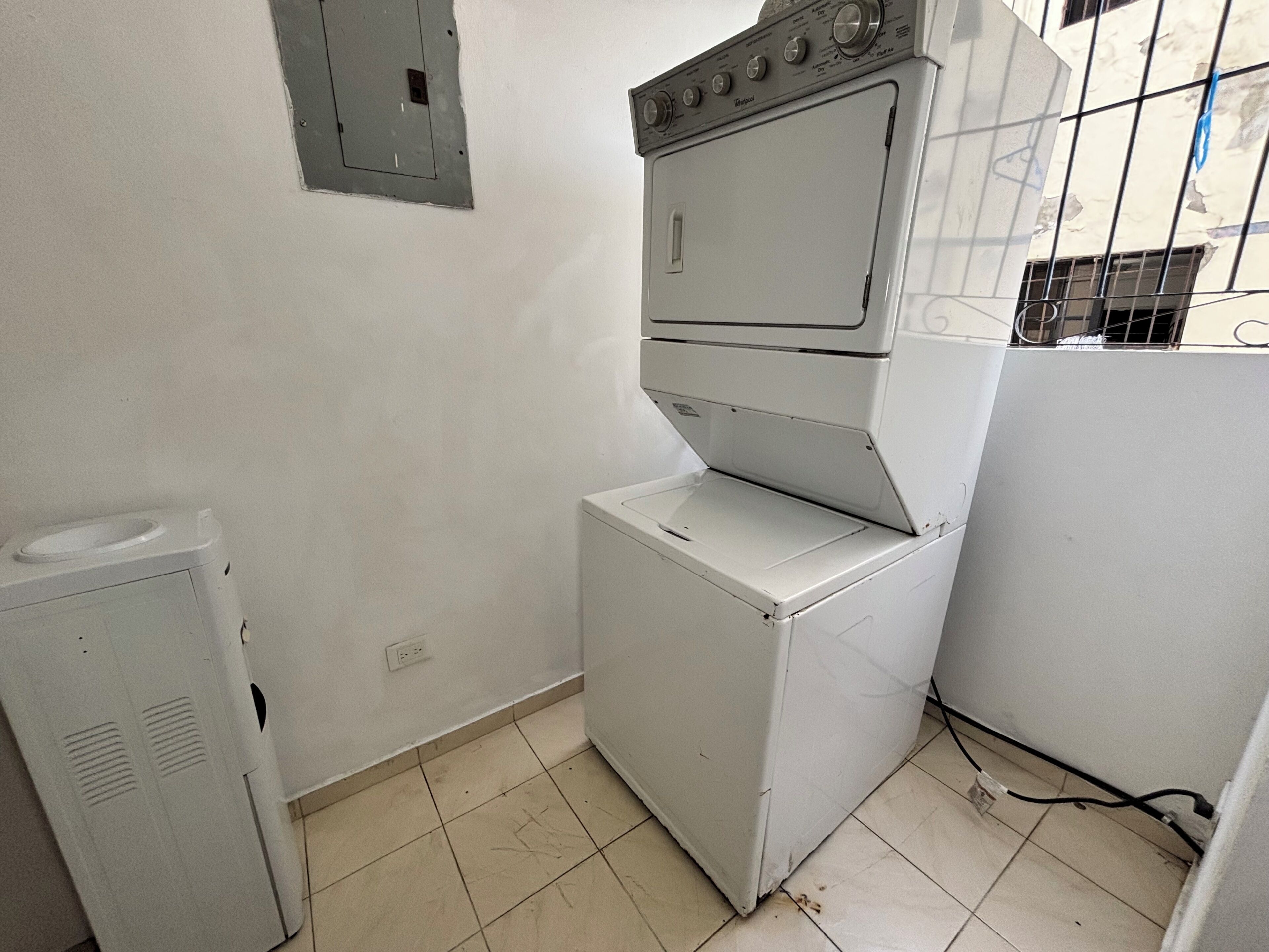 A compact laundry room with a washing machine, a dryer, and a small utility cabinet.
