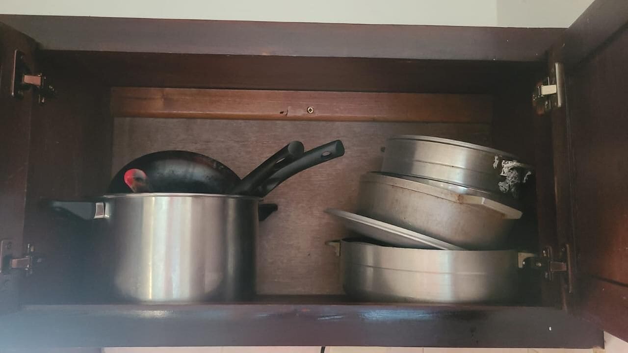 Un armario de cocina con ollas y sartenes de acero inoxidable.
