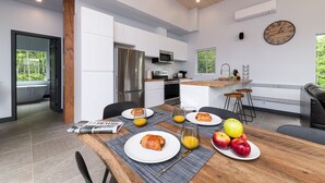 Una cucina moderna con mobili bianchi, elettrodomestici in acciaio inossidabile e un tavolo da pranzo in legno apparecchiato con piatti e bevande.