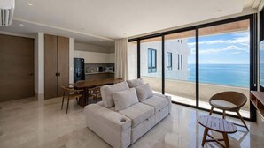 Una sala de estar moderna con un sofá, una mesa de comedor y sillas. Hay un ventanal con vistas al mar.