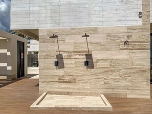 A modern building with a stone facade, two water features, and a parking area.