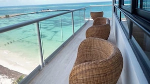 A balcony with wicker chairs, a glass railing, and a view of the ocean. - Beachfront 3BR Puerto Morelos - Rooftop Pool (Puerto Morelos)