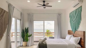 Ein Schlafzimmer mit Bett, Deckenventilator, Topfpflanze und Meerblick.